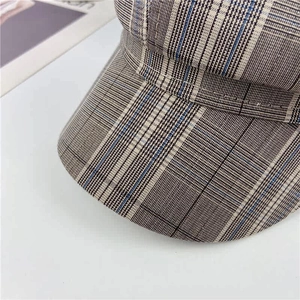 Close-up of the retro plaid newsboy hat showing brown-grey fabric and fine stitching