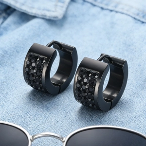 Detail of black huggie earrings with pavé crystals on blue denim background