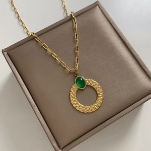Vintage gold twist ring necklace with green zircon pendant on jewelry box display