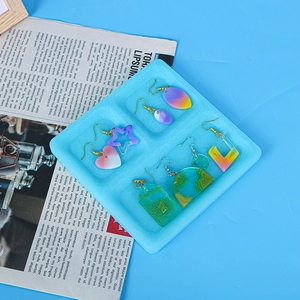 Close-up of colorful resin earrings in heart and star shapes inside a blue jewelry tray