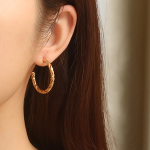 Minimalist twisted gold hoop earrings for women showing on model ear lobe profile