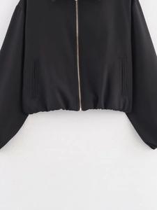 Detail der schwarzen Freizeitjacke mit goldenem Metallreißverschluss und Saum