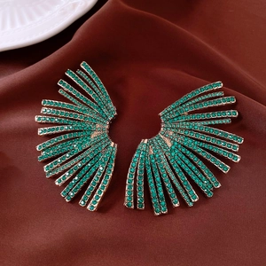 Vue détaillée de grandes boucles d'oreilles en éventail avec strass verts sur soie brune
