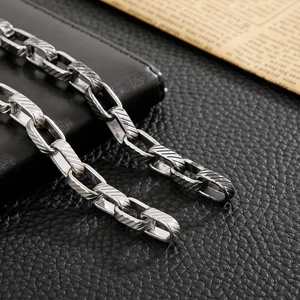 Detail of vintage steel link chain with engraved textures on a black leather surface
