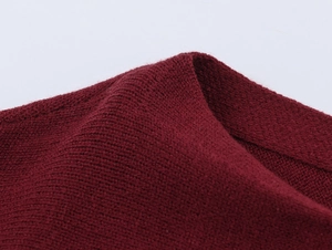 Close-up of wine red knit fabric showing detailed ribbed texture and soft fibers