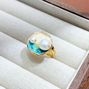 Détail de bague dorée style peinture à l'huile avec émail bleu et perles naturelles