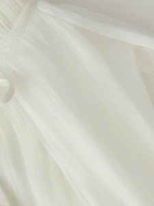Macro view of white pleated chiffon fabric showing fine stitching on the dress hem