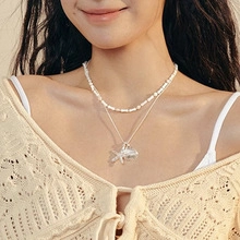 Detail of layered freshwater pearl necklace with silver starfish pendant on model neck