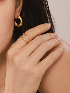 Detailed close-up of a gold-plated interlocking hollow ring and matching hoop earrings