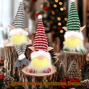 Three lighted Christmas gnomes with striped hats on wooden stands in a warm festive setting