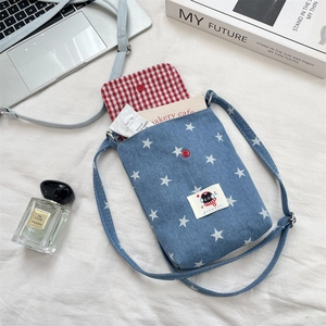 Detail van denim crossbody telefoontas met sterpatronen en rode drukknoopsluiting