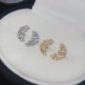 Detailed close-up of crescent moon earrings with inlaid pearls and sparkling cubic zirconia