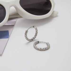 Detail of silver hammered texture hoop earrings with hinge closure on white background