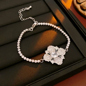 Gros plan d'un bracelet fleur argenté orné de cristaux sur un présentoir en cuir noir