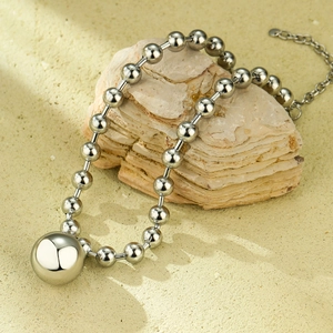 Close-up of polished stainless steel ball pendant on a sleek beaded chain necklace