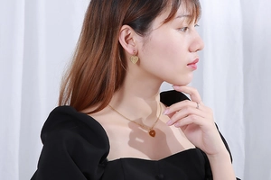 Close-up of golden multi-layer hollow heart necklace and matching earrings on a model