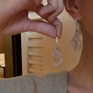 Silver hollow zircon drop earrings featuring a geometric leaf design on a model