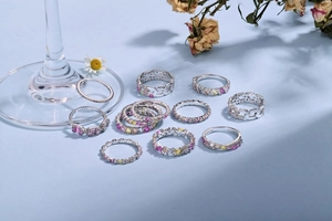 Flat lay of diverse S925 silver rings with colorful cubic zirconia on blue background