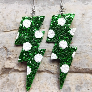 Dettaglio degli orecchini a fulmine verdi glitterati con pois bianchi su fondo pietra