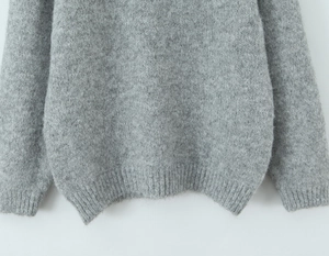 Detail of the ribbed hem and soft wool texture on a classic grey knit sweater