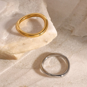 Polished wavy stainless steel rings in gold and silver finish on natural stone