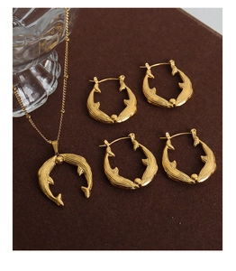 Detailed view of golden fish tail necklaces and matching textured earrings jewelry set