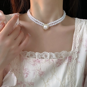 Détail d'un collier double rangée de perles avec pendentif ovale doré sur un mannequin
