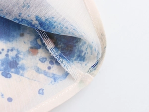 Κοντινή λήψη μπλε tie-dye σχεδίου σε ελαφρύ λευκό ύφασμα με προσεγμένη ραφή στο τελείωμα