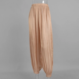 Detailed close-up of glossy pleated satin harem pants with elastic high waist and cuffed ankles