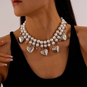 Detail of double-layer faux pearl necklace with silver heart pendants on model