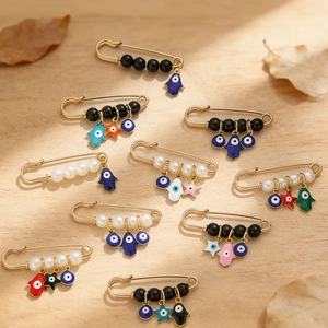 Détail d'épingles de sûreté Evil Eye dorées avec pendentifs Hamsa sur fond bois