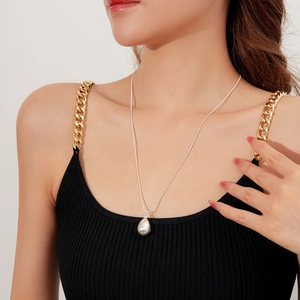 Gros plan du collier avec pendentif goutte d'argent minimaliste sur tenue noire