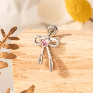 Minimalistischer silberner Schleifenohrring mit rosa Herz-Edelstein auf Holzgrund