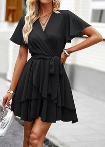 Détail d'une robe noire à col en V avec ceinture à nouer et ourlet à volants étagés