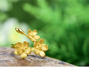 Detail of S925 silver flower ring with gold matte texture on a natural stone base