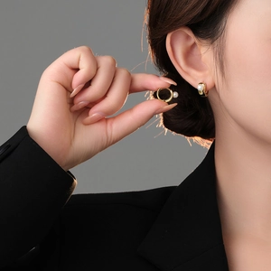 Close-up of minimalist gold pearl hoop earrings on ear with high metallic luster