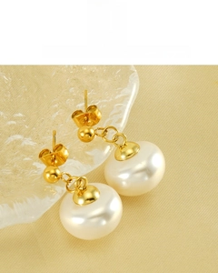 Detail of 18K vacuum plated gold earrings with lustrous round pearls on silk background