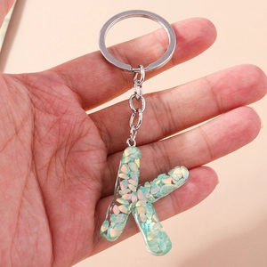 Detail of letter K keychain with green iridescent glitter in transparent resin