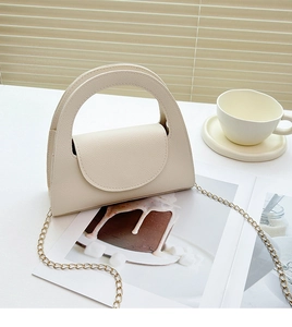 Chic beige lychee textured mini bag with golden chain on a stylish minimalist tabletop