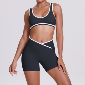 Detail of cross-waist yoga shorts and contrast trim sports bra in black breathable fabric