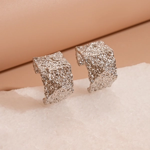 Silver geometric C-shaped hoop earrings with unique hammered foil texture on a stone base