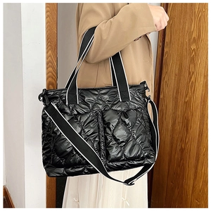 Detail of black quilted puffer tote bag with glossy waterproof nylon and woven handles