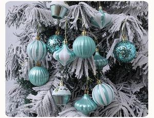 Close-up of teal and white glitter Christmas ornaments on a snow-covered tree branch