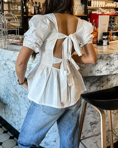 Détail d'un haut blanc dos nu avec nœud papillon et manches bouffantes sur mannequin