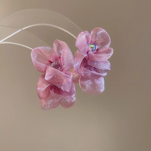 Macro detail of pink chiffon flower earrings with shimmering rhinestone centers