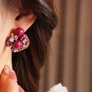 Detailed close-up of a vintage magenta petal earring with sparkling crystals on a model