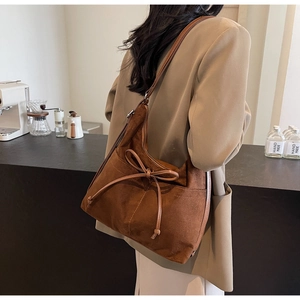 Detail of a brown vintage suede shoulder bag featuring a stylish decorative bow knot
