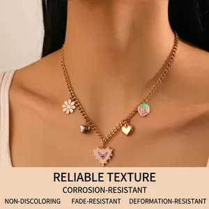 Detail of gold stainless steel necklace with enamel heart, strawberry and floral charms
