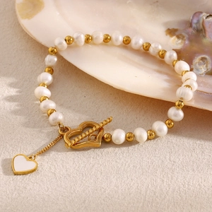 Detail of pearl heart toggle bracelet with gold beads and white enamel heart charm