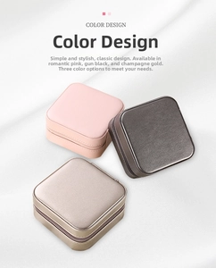 Overhead view of portable square leather jewelry boxes in pink, grey and gold finishes